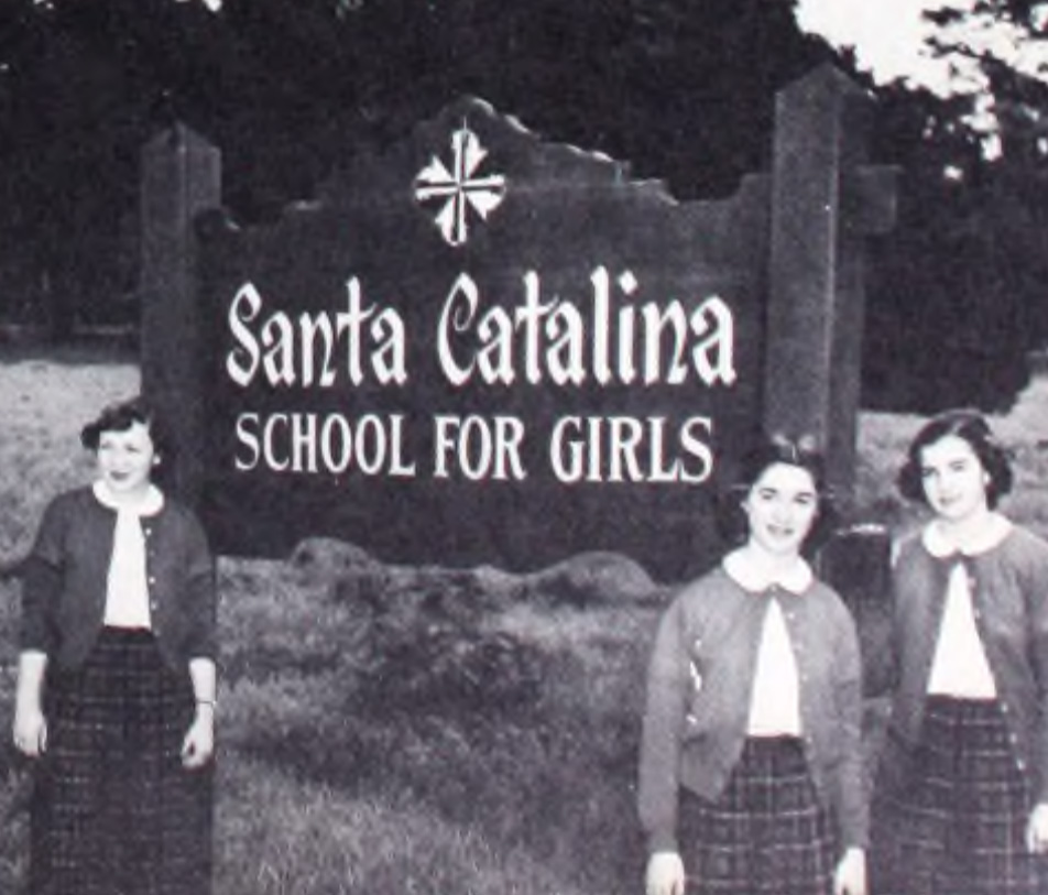 In a photo from the 1950s, three students in uniform flank a sign that reads Santa Catalina School for Girls.